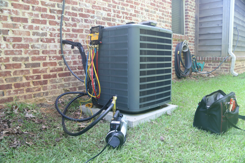 Air conditioner maintenance being performed with gauges and vacuum pump